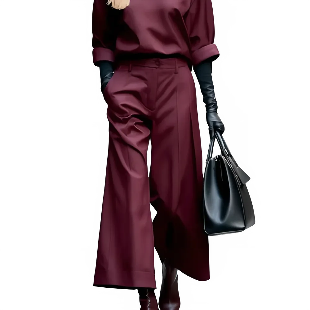 Woman in burgundy wide-leg pants and top, black gloves, holding a large black handbag
