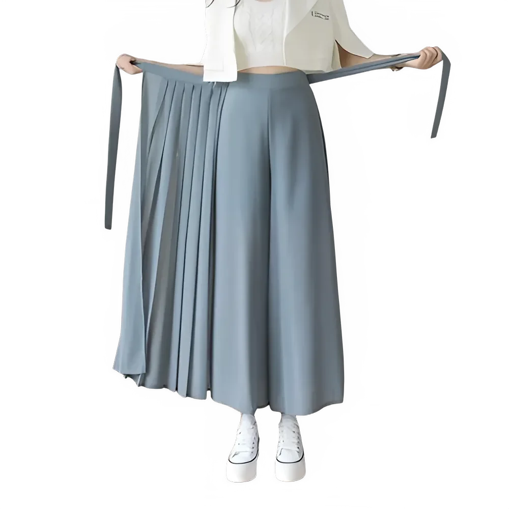 Woman wearing a blue pleated wide-leg skirt with long waist ties and white sneakers