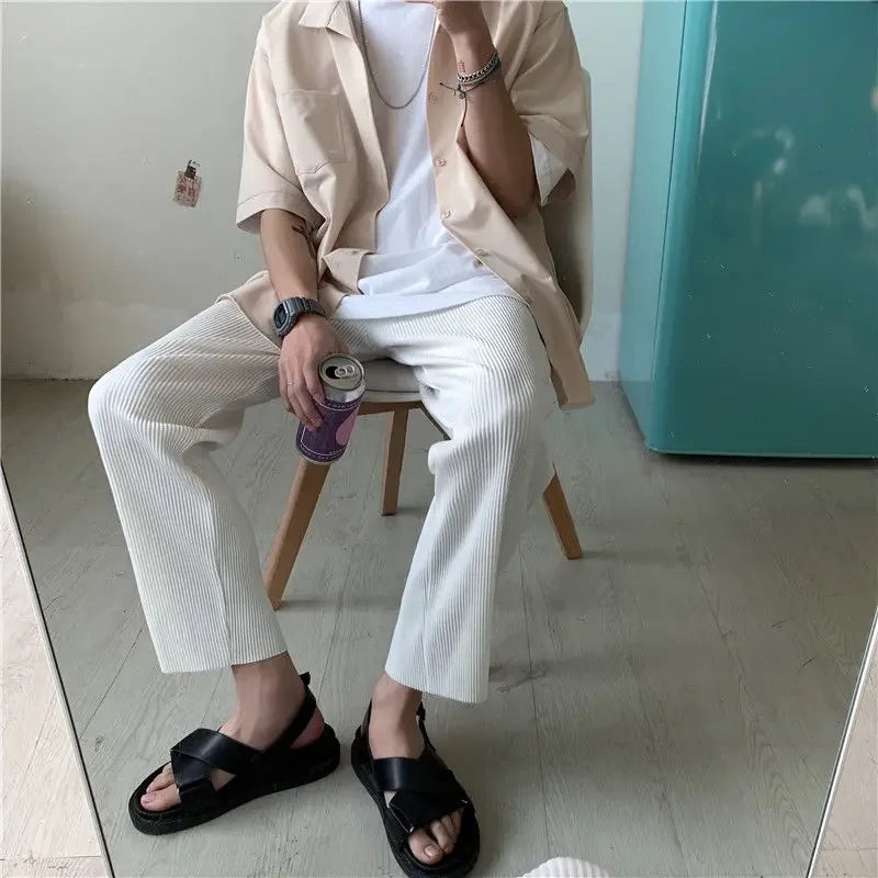 Casual summer men's outfit with beige shirt, white pants, sandals, holding a soda can