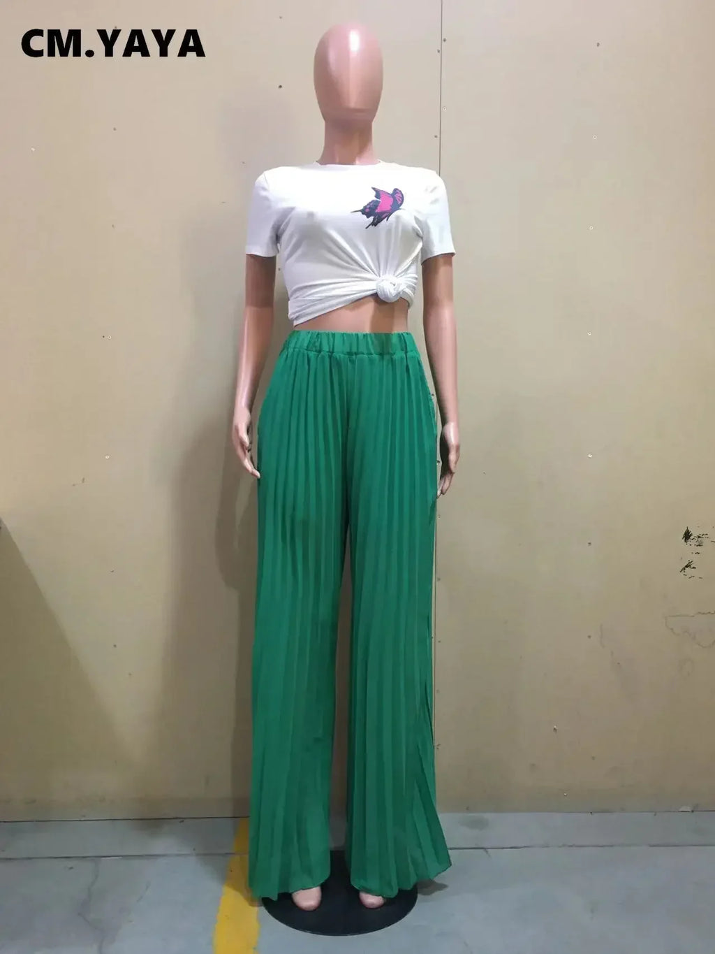 Mannequin in white knotted crop top with bird graphic and green pleated wide leg pants