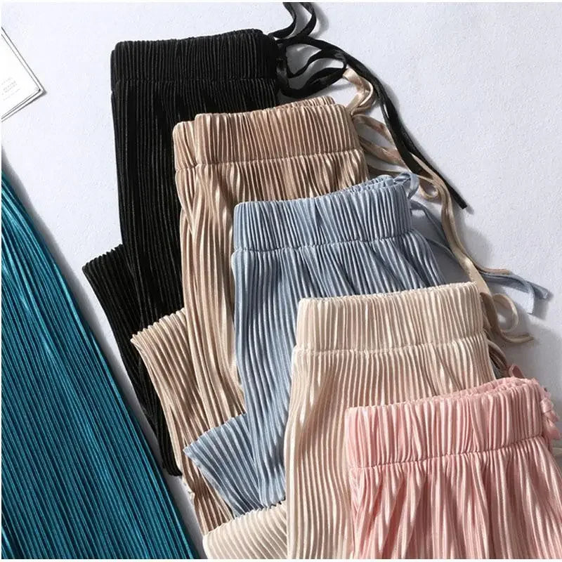 Assorted pleated wide-leg pants in black, beige, blue, cream, pink and teal on a white background