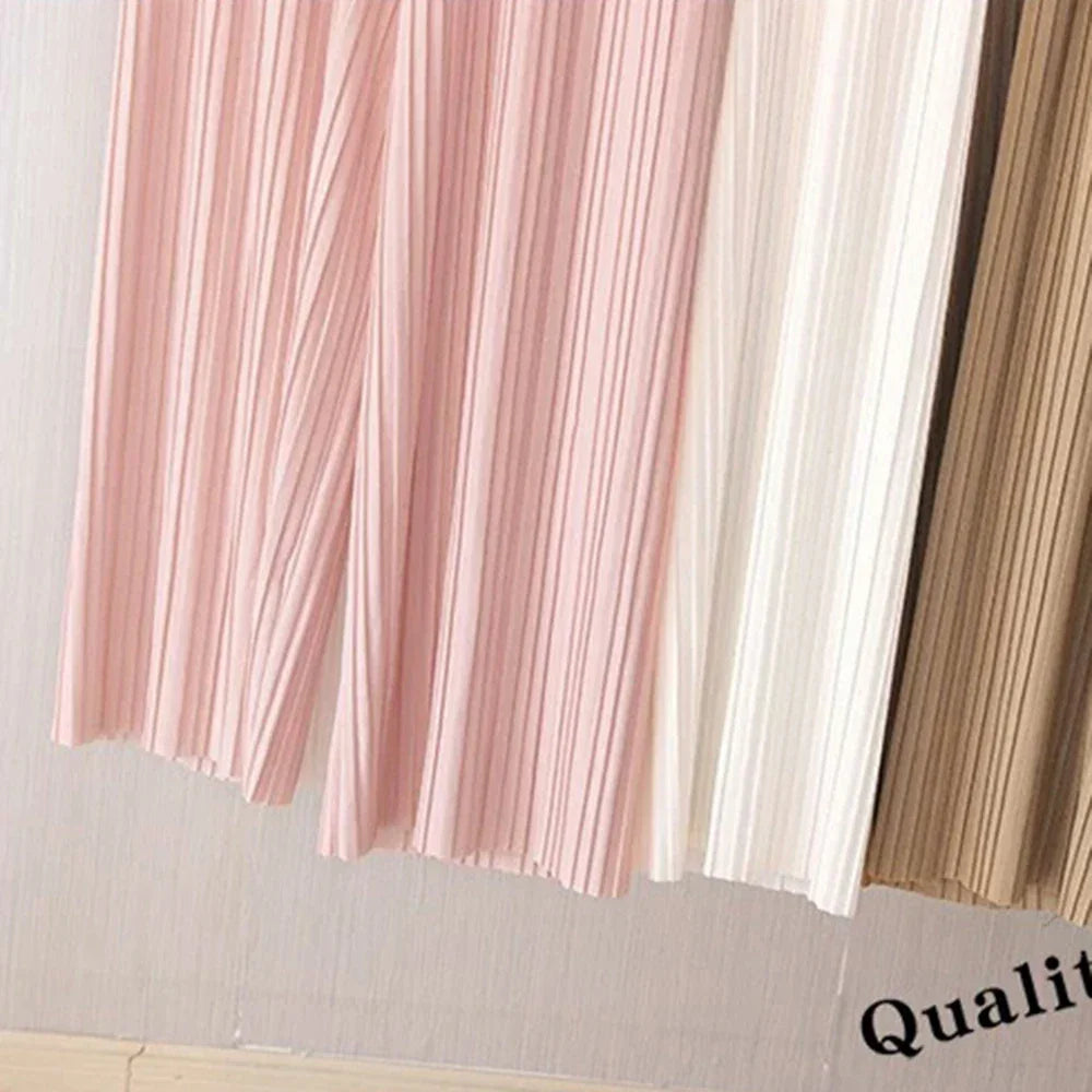 Pastel pleated skirts in pink, cream, and beige hanging indoors
