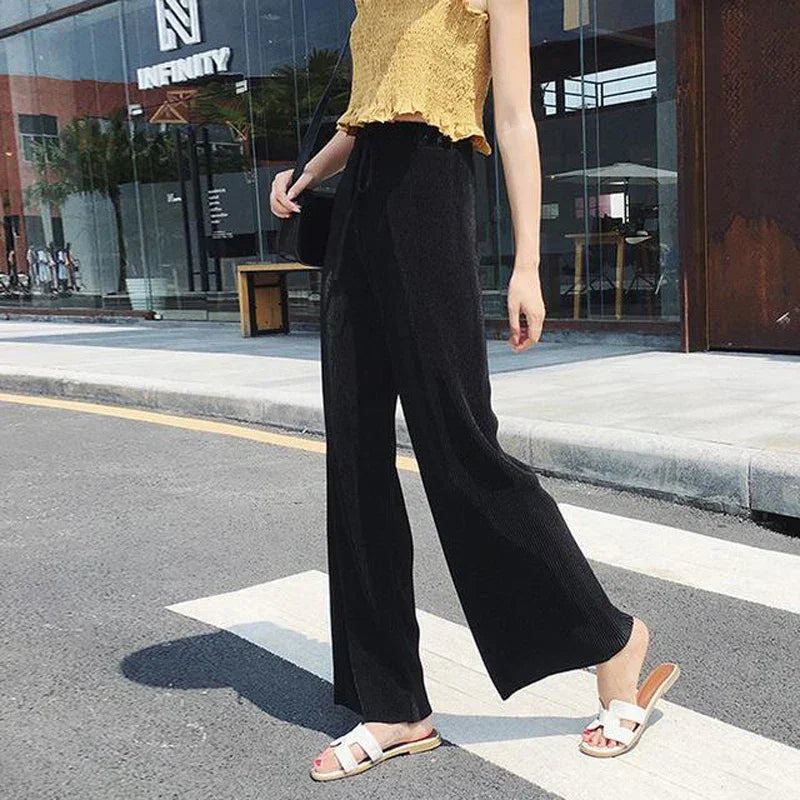 Woman wearing high-waisted black wide-leg pants and yellow crop top outdoors