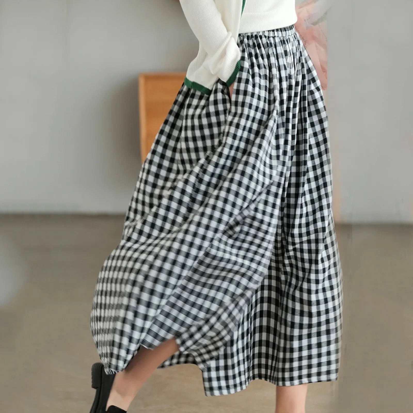Woman wearing black and white gingham check midi skirt indoors