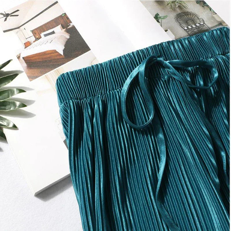 Teal pleated satin skirt with drawstring waistband, styled on magazine background