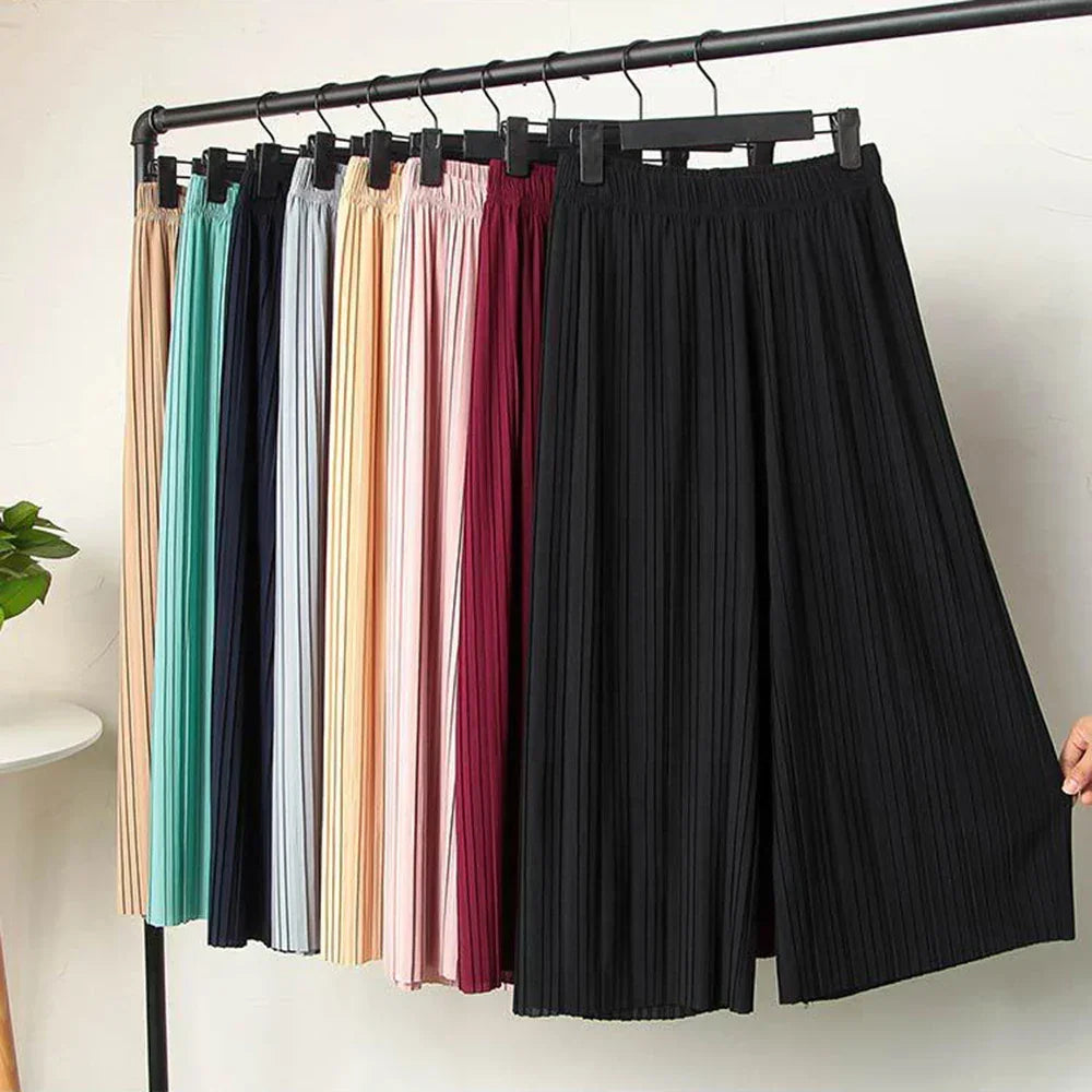 Pleated wide leg pants in assorted colors hanging on a clothing rack