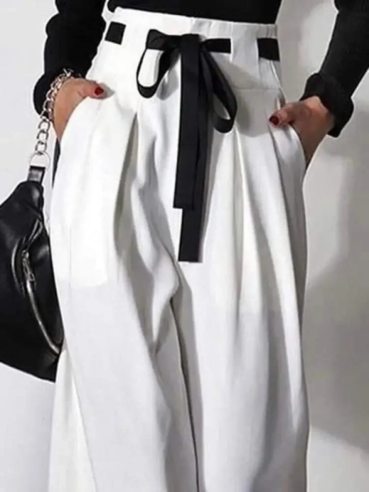 High-waisted white wide leg pants with black ribbon belt and pockets, styled with black top