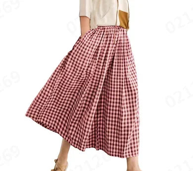 Woman wearing a red and white gingham midi skirt with pleats, beige top, and sandals