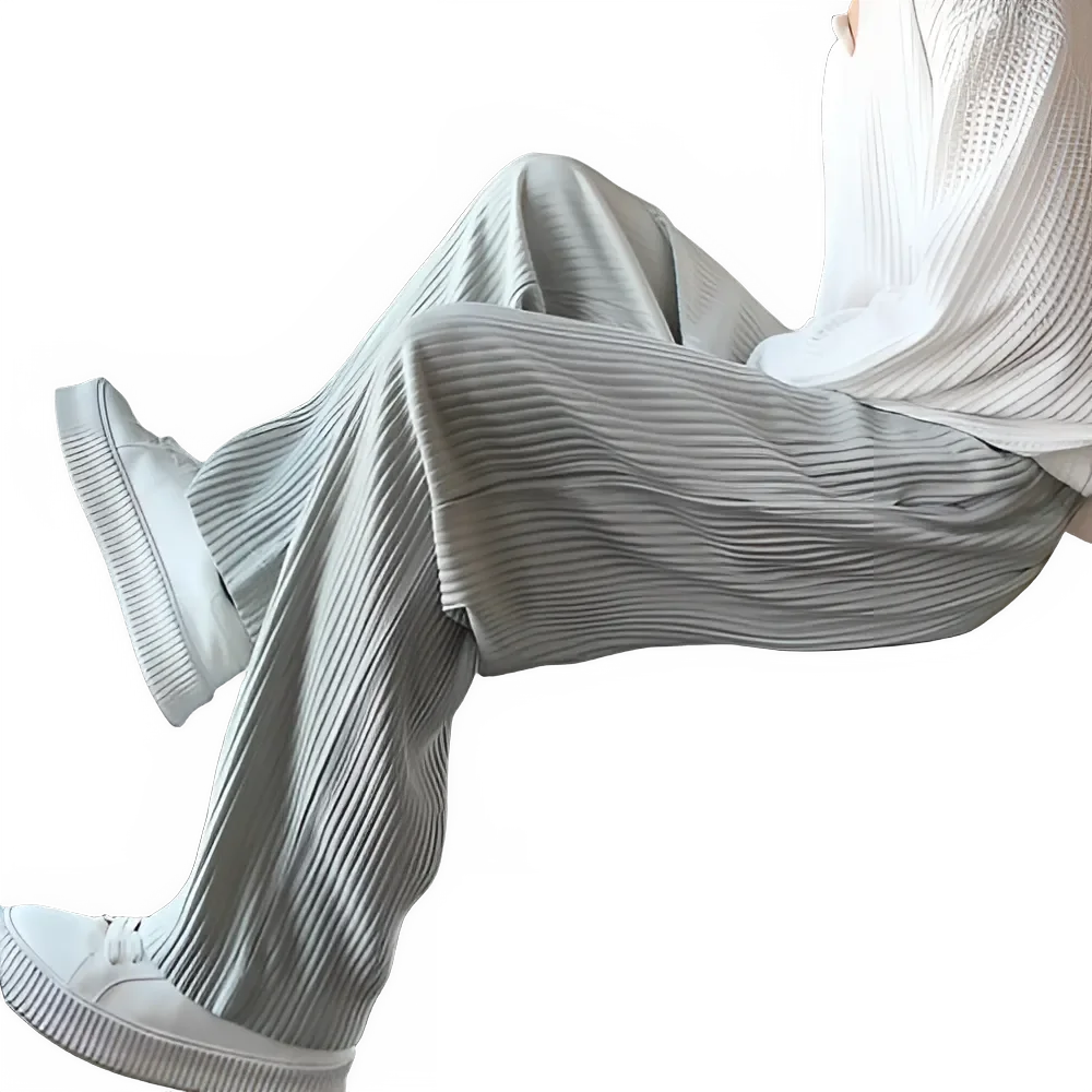 Woman in pleated wide-leg pants, white sweater, and platform sneakers on black background
