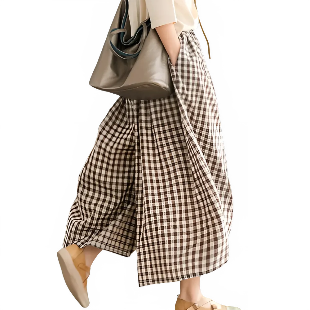 Woman wearing wide-leg brown plaid pants, beige shoes, and carrying a gray tote bag